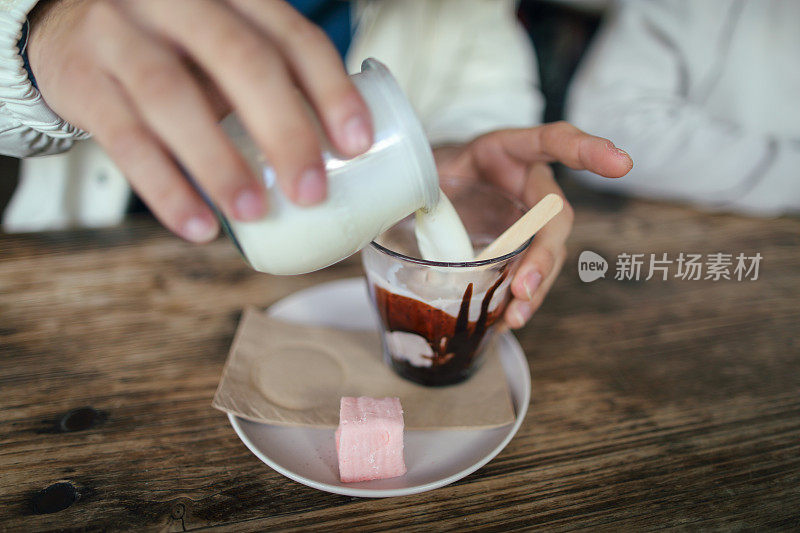 英语
The Asian boy  is pouring hot milk into hot chocolate to make hot chocolate milk